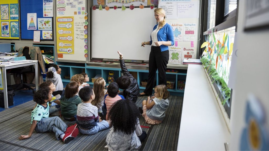 Teacher in front of class with her engaged primary students sitting in whole group.